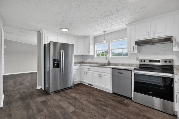 a kitchen with granite countertop a refrigerator stove and sink