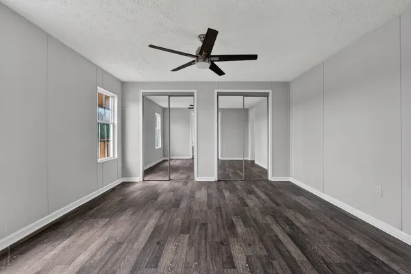 a view of empty room with wooden floor and ceiling fan
