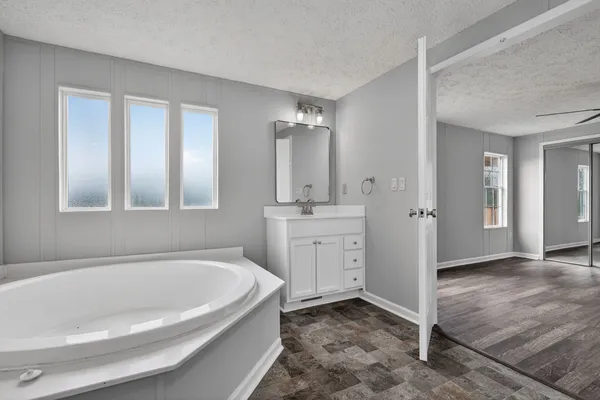 a spacious bathroom with a tub sink and mirror