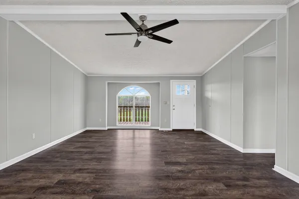 a view of an empty room with a window and wooden floor