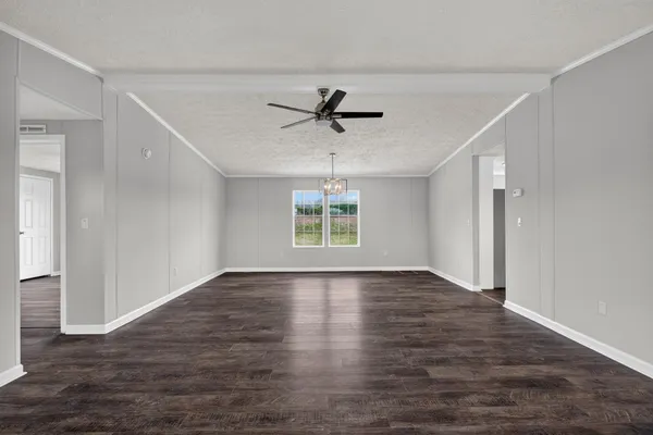 an empty room with wooden floor chandelier fan and windows