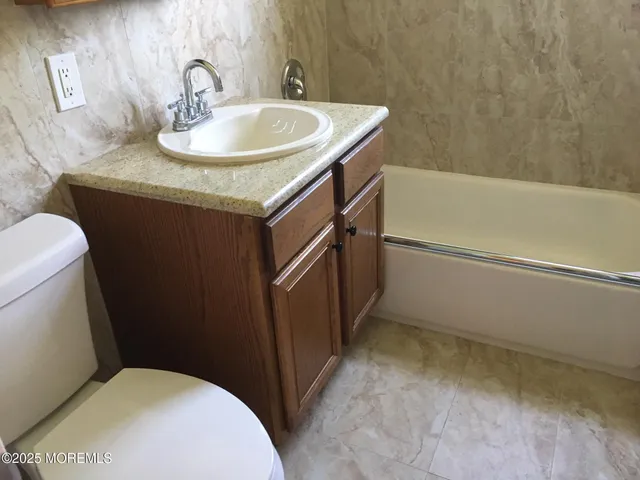 a bathroom with a granite countertop sink toilet and a bathtub