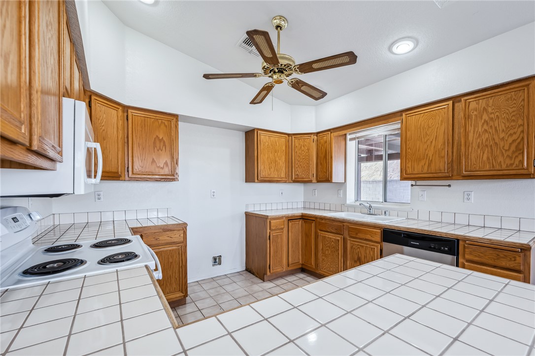 2524 South Ridge Avenue Bullhead City, AZ 86429 - Photo 26 of 64 Kitchen with tile countertops, white appliances, a sink, brown cabinets, and ceiling fan