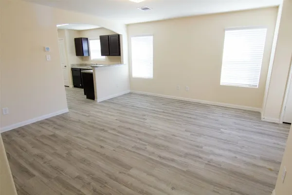 an empty room with wooden floor cabinet and windows