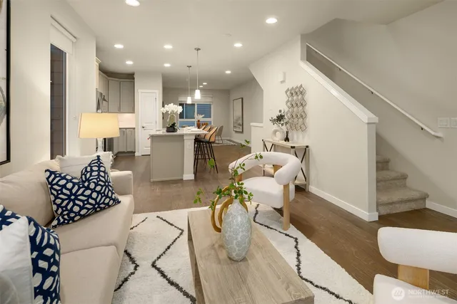a living room with furniture kitchen view and a wooden floor