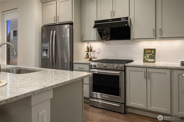 a kitchen with granite countertop a sink stove and refrigerator