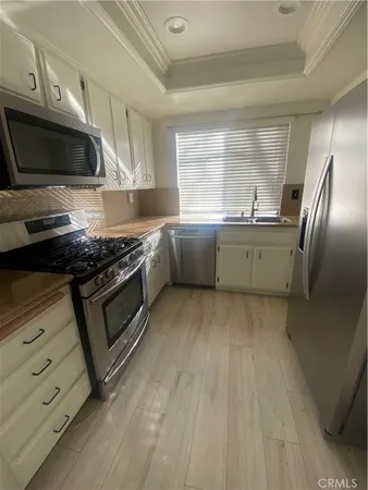 a kitchen with stainless steel appliances a refrigerator a sink dishwasher a stove and white cabinets