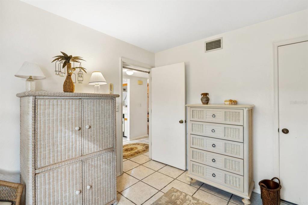 2275 South McCall Road, Unit 102 Englewood, FL 34224 - Photo 24 of 48 a bedroom with a dresser and a chandelier