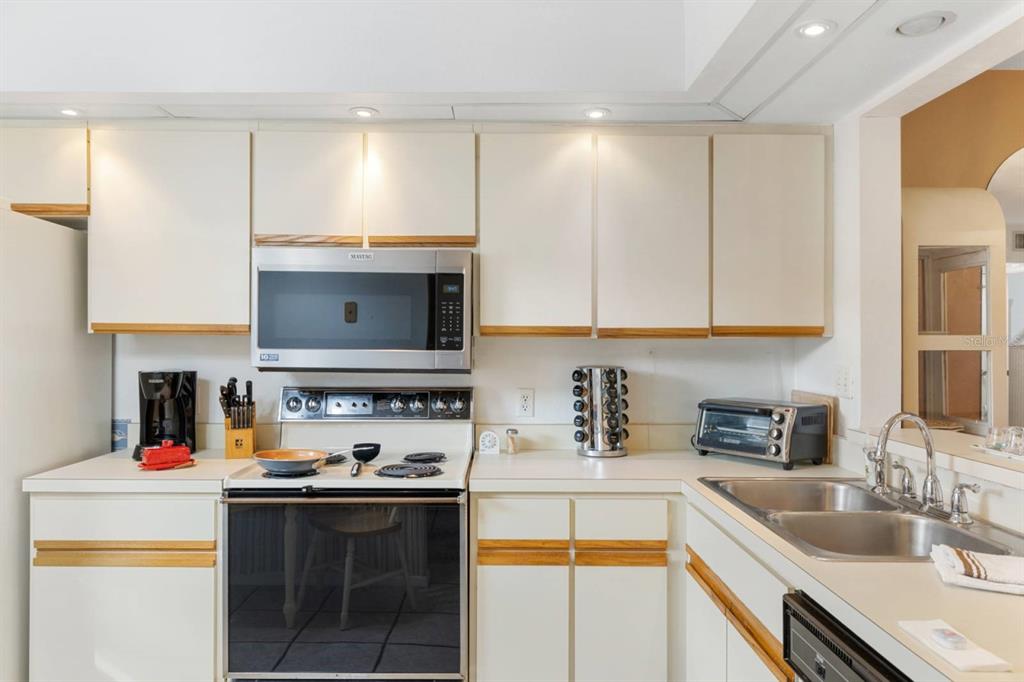 2275 South McCall Road, Unit 102 Englewood, FL 34224 - Photo 7 of 48 a kitchen with stainless steel appliances a sink stove and cabinets