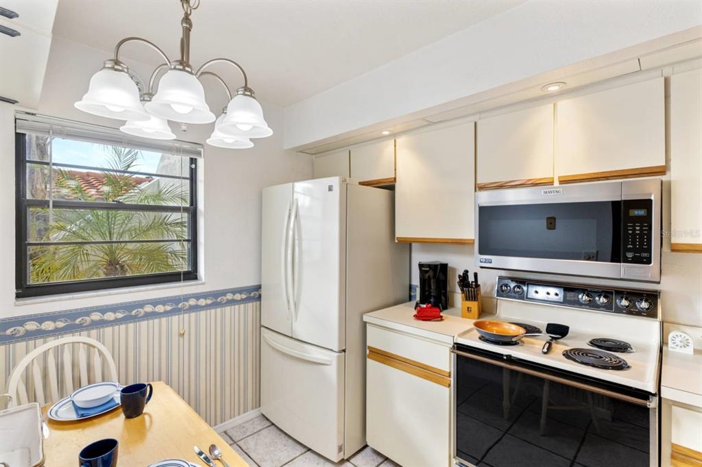 2275 South McCall Road, Unit 102 Englewood, FL 34224 - Photo 10 of 48 a kitchen with stainless steel appliances granite countertop a refrigerator and a stove top oven
