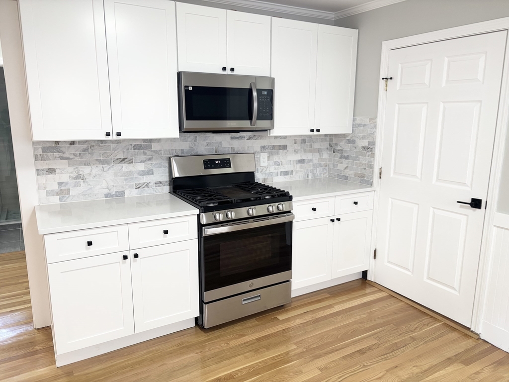 73 Dent Street, Unit 1 Boston, MA 02132 - Photo 11 of 36 a kitchen with granite countertop a stove and a microwave