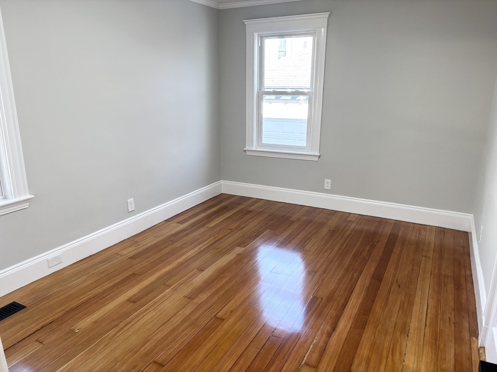 73 Dent Street, Unit 1 Boston, MA 02132 - Photo 18 of 36 an empty room with wooden floor and windows