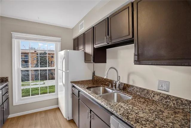 a kitchen with granite countertop a sink a stove and a wooden floor