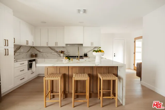 a kitchen with granite countertop a table chairs stove and white cabinets