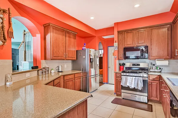 a kitchen with stainless steel appliances granite countertop a refrigerator a stove and a sink with wooden cabinets