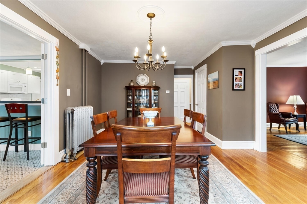 687 Main Street Wakefield, MA 01880 - Photo 14 of 36 a dining room with wooden floor a chandelier a wooden table and chairs