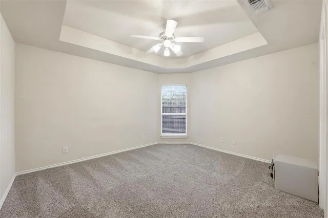 an empty room with a chandelier fan and windows