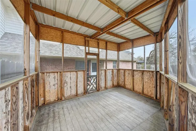 a view of an empty room with wooden floor and iron stairs