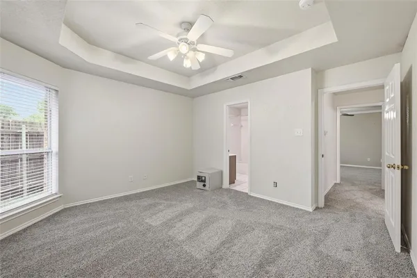 an empty room with windows and fan