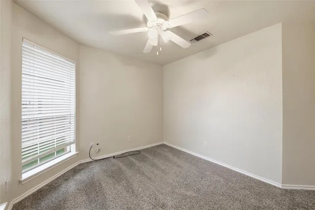 an empty room with a window and a fan
