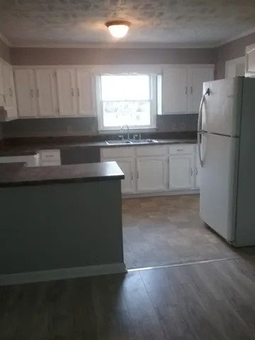 a kitchen with granite countertop a refrigerator and a sink