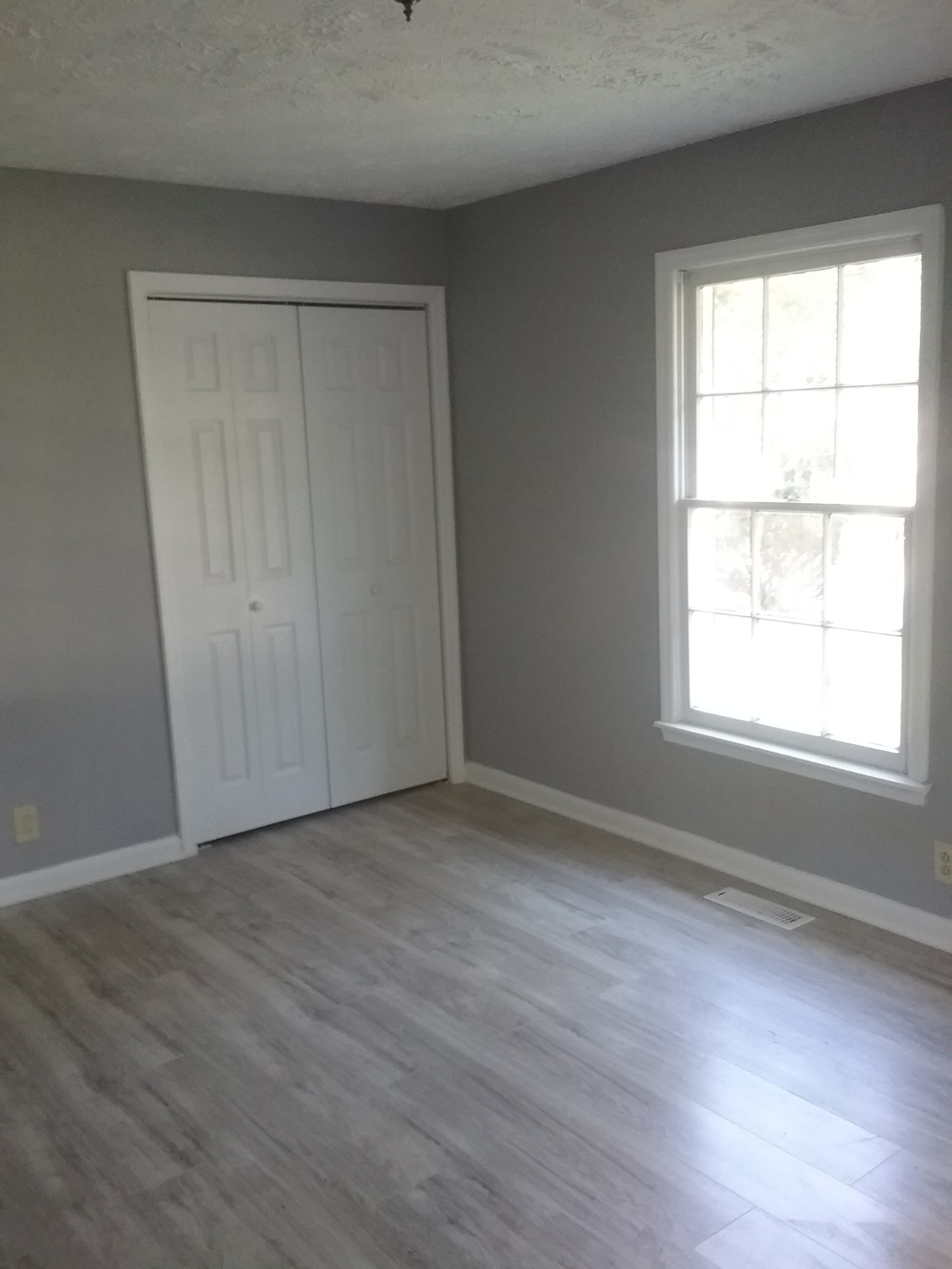 211 Locust Street Alexandria, TN 37012 - Photo 8 of 13 an empty room with wooden floor and windows with curtains