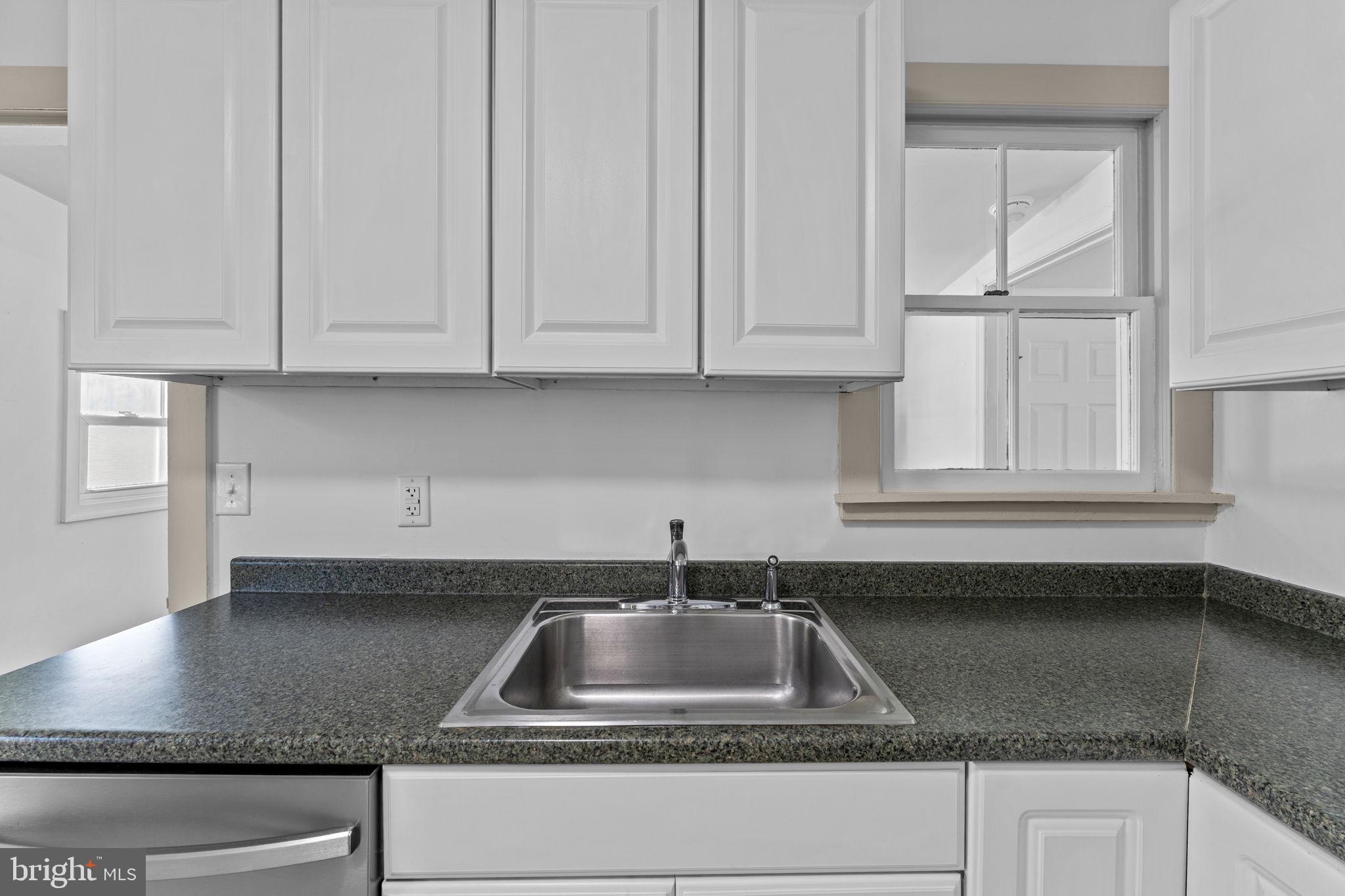 216 Walnut Street Berryville, VA 22611 - Photo 25 of 36 a kitchen with granite countertop a sink a window and cabinets