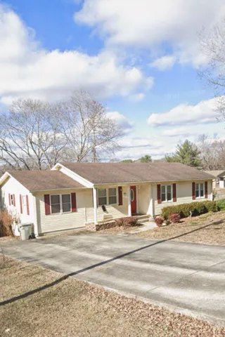 a view of a white house with a dining table and chairs