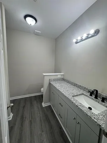 a bathroom with a granite countertop sink toilet and a mirror