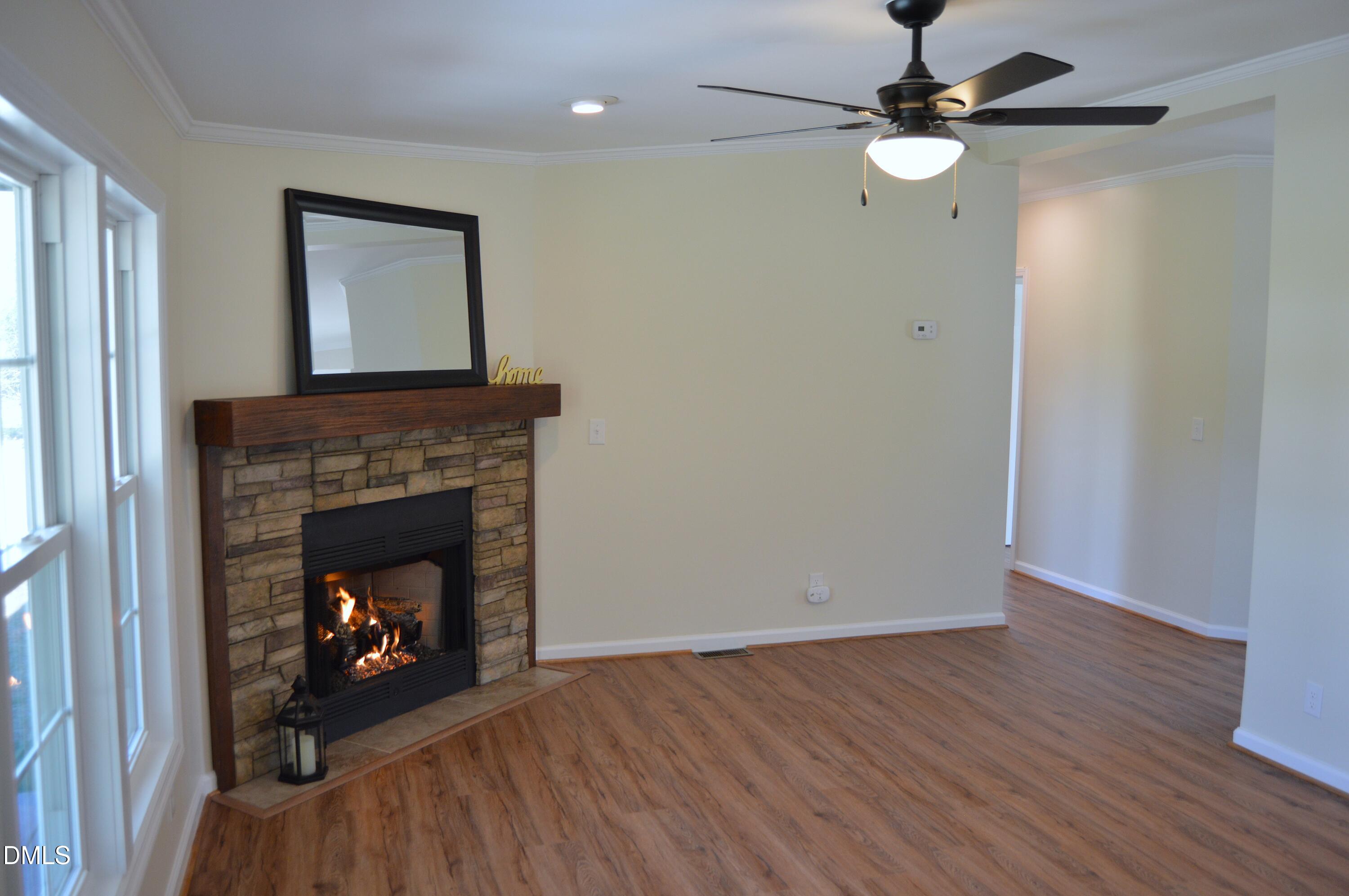 1159 No Bottom Road Warrenton, NC 27589 - Photo 10 of 44 a living room with wooden floor a fireplace a ceiling fan and a window