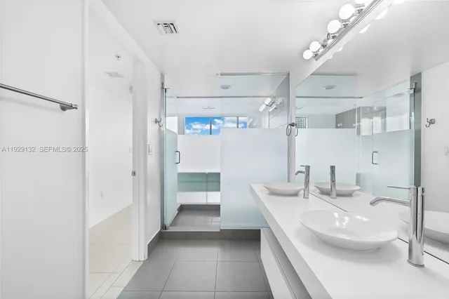 a bathroom with a double vanity sink mirror and shower