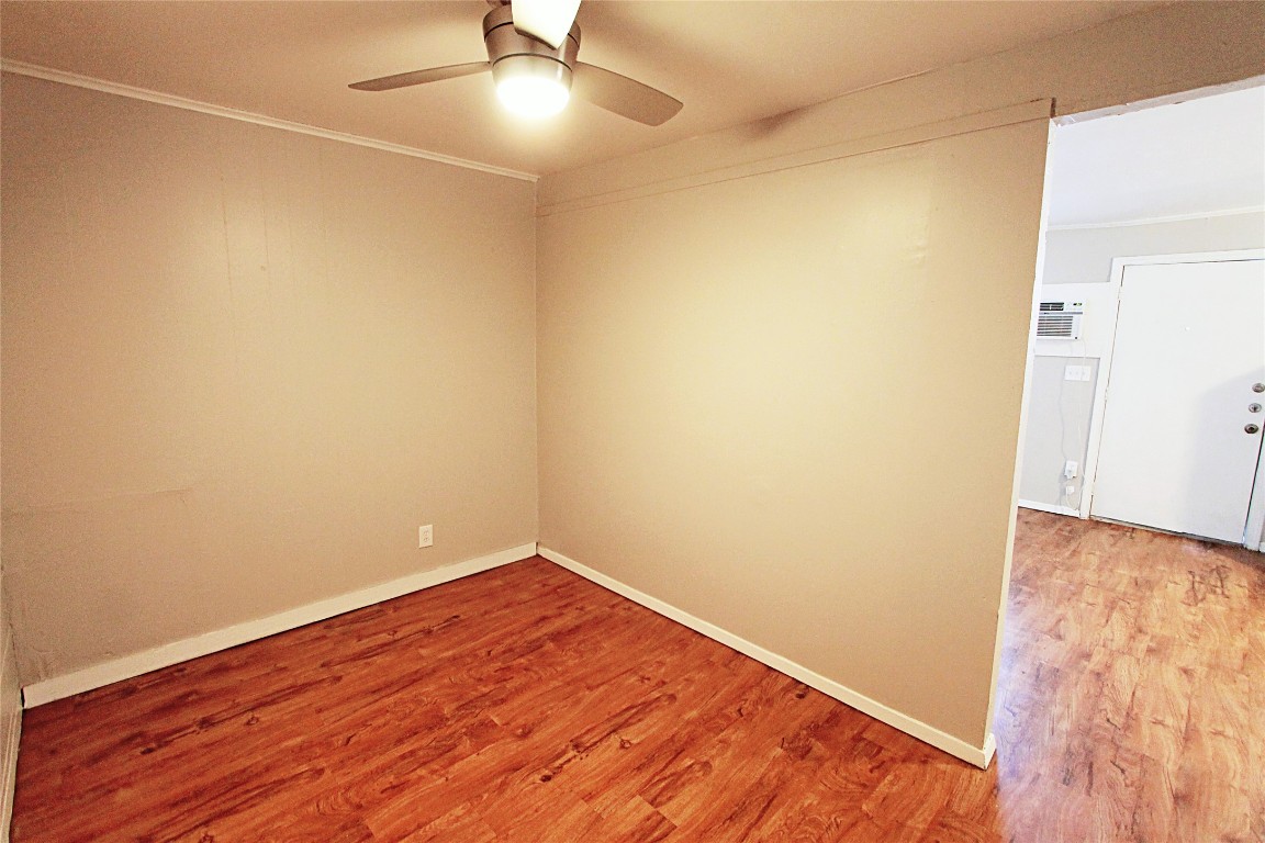 901 Springdale Road, Unit 102 Austin, TX 78702 - Photo 11 of 17 Empty room featuring wood finished floors, crown molding, and ceiling fan