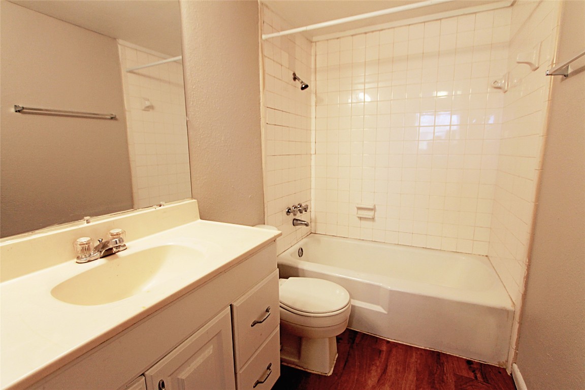 901 Springdale Road, Unit 102 Austin, TX 78702 - Photo 15 of 17 Bathroom featuring shower / bathtub combination, vanity, dark wood-style flooring, and a textured wall