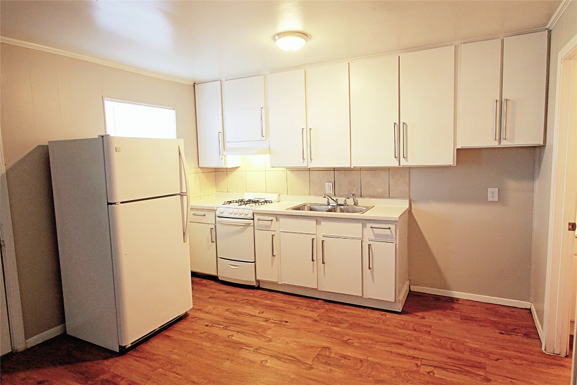 901 Springdale Road, Unit 102 Austin, TX 78702 - Photo 16 of 17 Kitchen with white appliances, light countertops, light wood-style floors, extractor fan, and white cabinetry