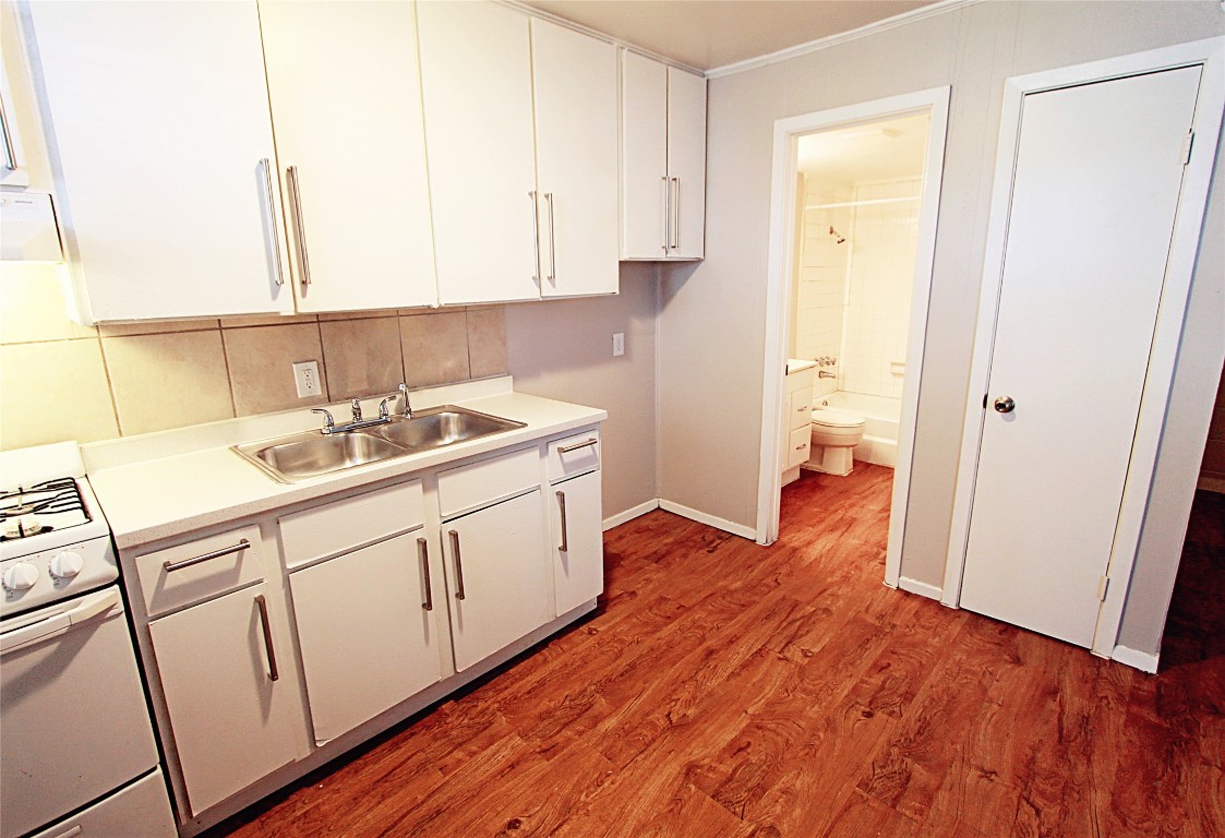 901 Springdale Road, Unit 102 Austin, TX 78702 - Photo 9 of 17 Kitchen with gas range gas stove, light countertops, light wood-style flooring, crown molding, and exhaust hood