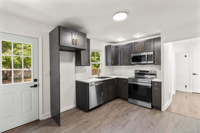 a kitchen with stainless steel appliances granite countertop a stove top oven a sink and dishwasher a refrigerator with wooden floor