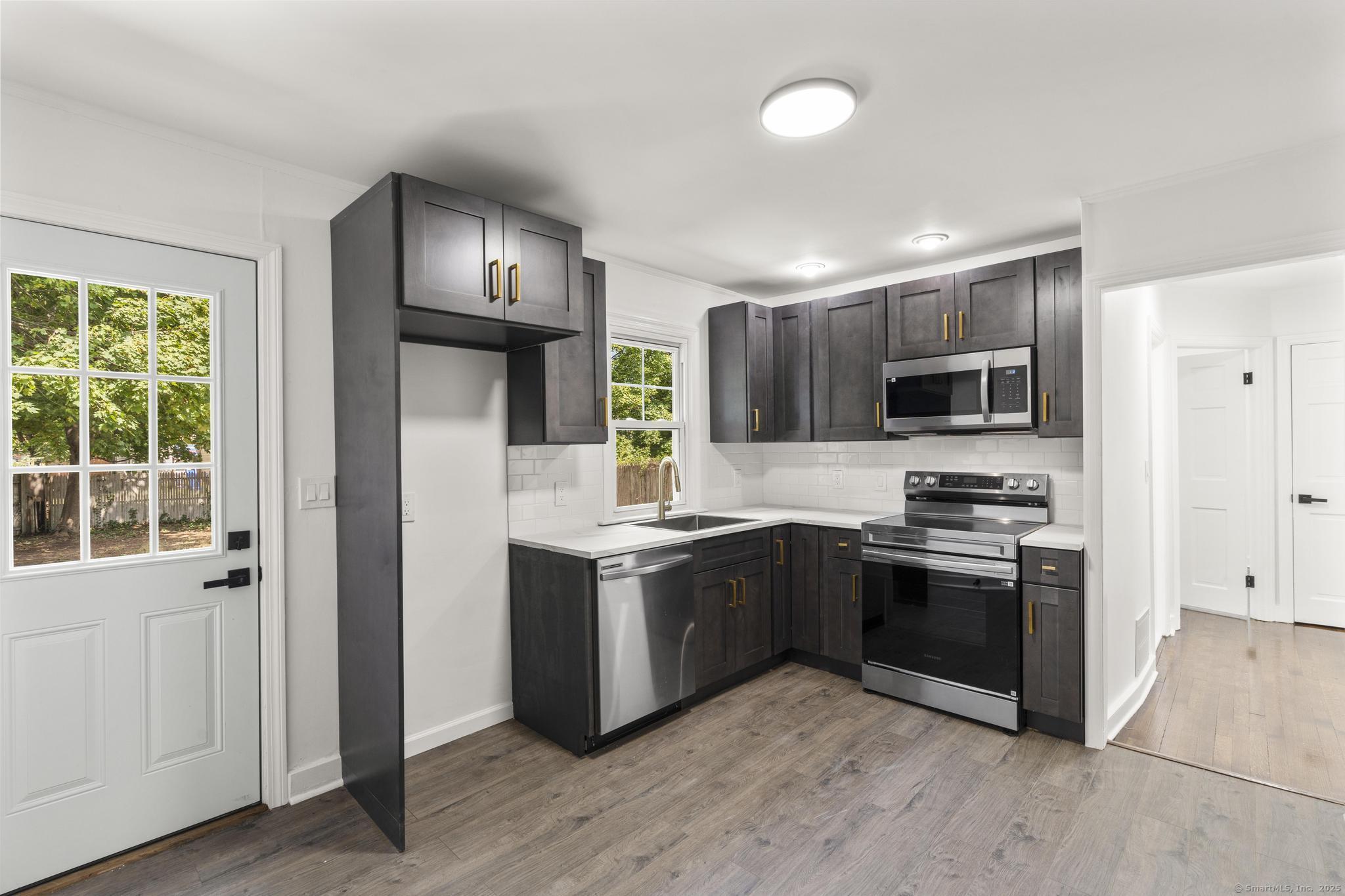 203 Gorham Avenue Hamden, CT 06514 - Photo 13 of 31 a kitchen with stainless steel appliances granite countertop a stove top oven a sink and dishwasher a refrigerator with wooden floor