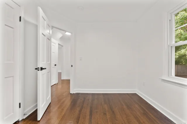 a view of a hallway with wooden floor and a window