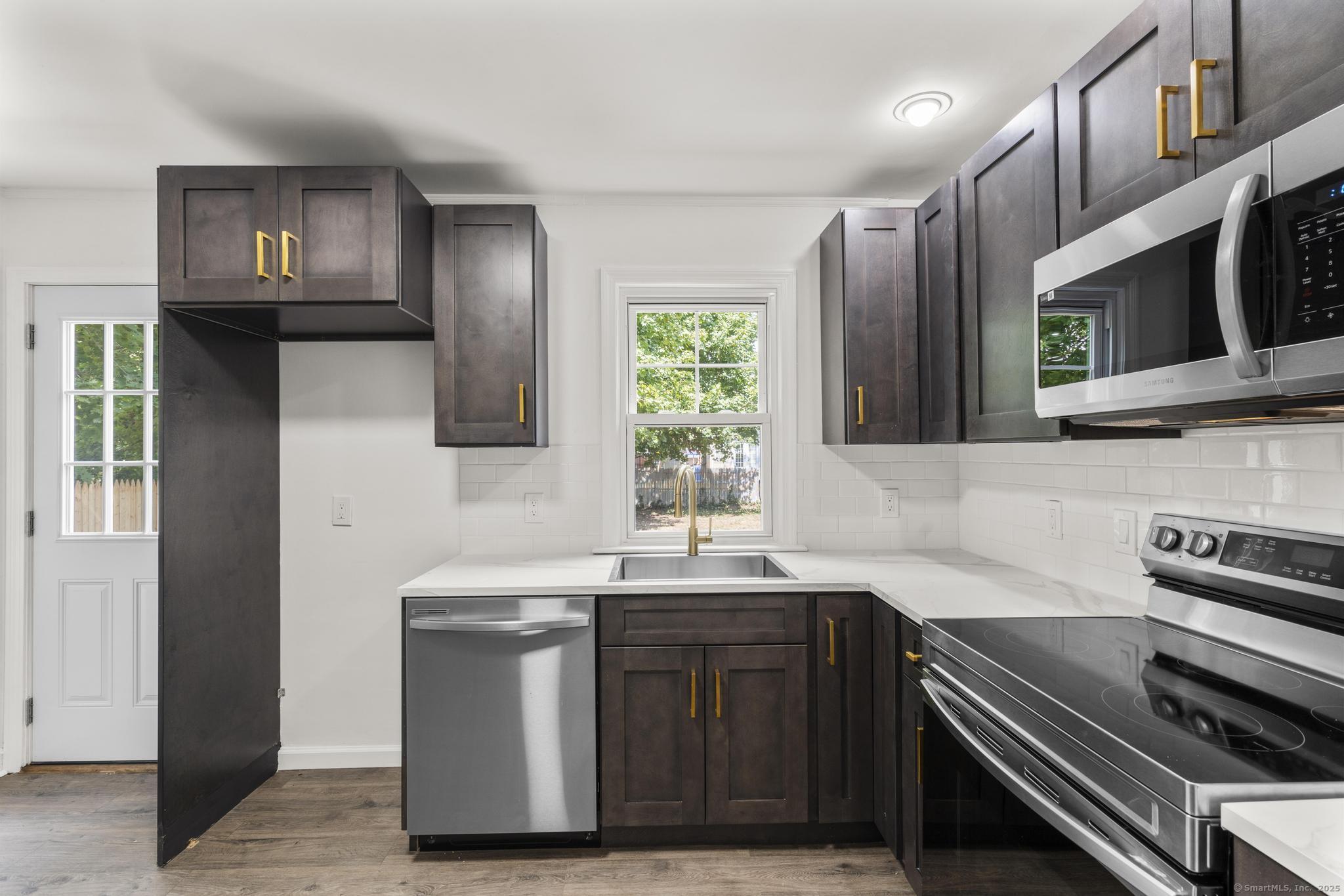 203 Gorham Avenue Hamden, CT 06514 - Photo 10 of 31 a kitchen with stainless steel appliances a sink a stove a microwave and cabinets