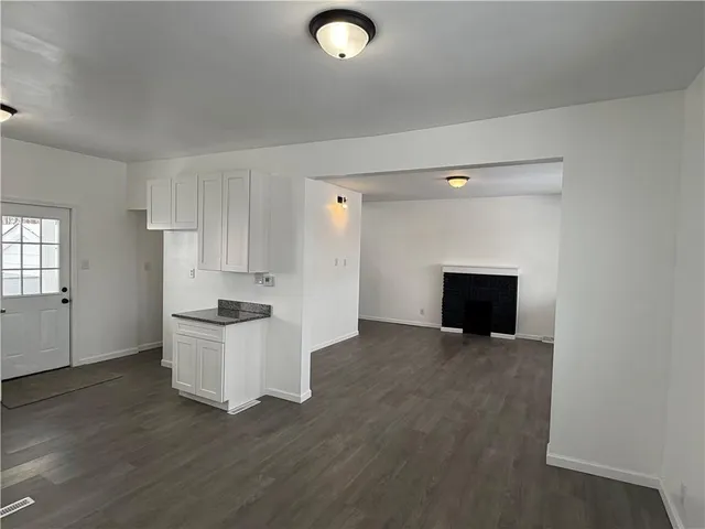 an empty room with a fireplace and wooden floor