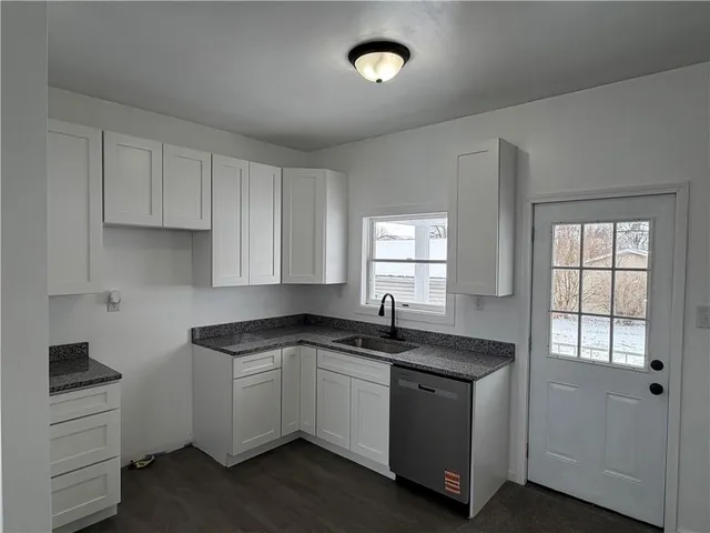 a kitchen with granite countertop a sink a stove and cabinets