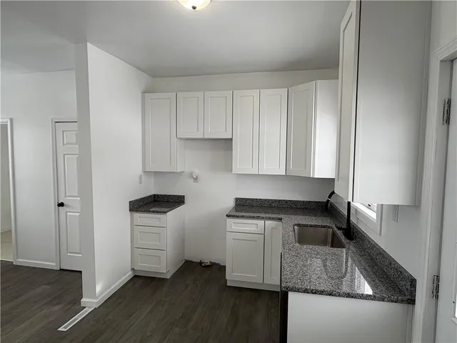 an empty room with wooden floor and cabinet