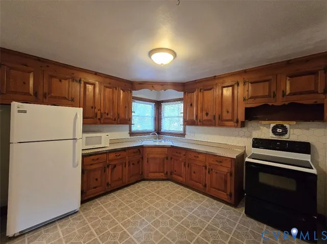 a kitchen with cabinets a sink and white appliances