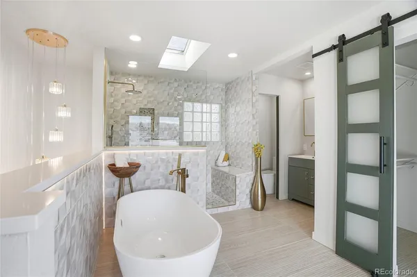 a bathroom with a tub shower sink and mirror