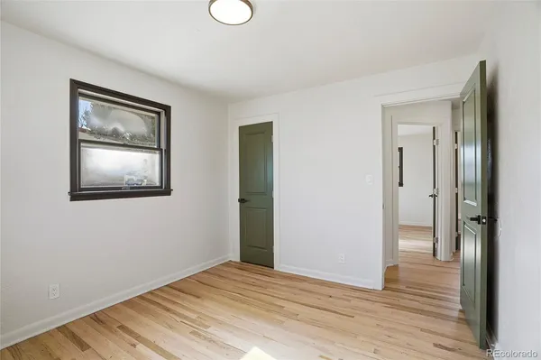 a view of an empty room with wooden floor and a mirror