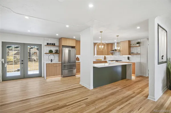 a large kitchen with a large counter top a sink stainless steel appliances and cabinets