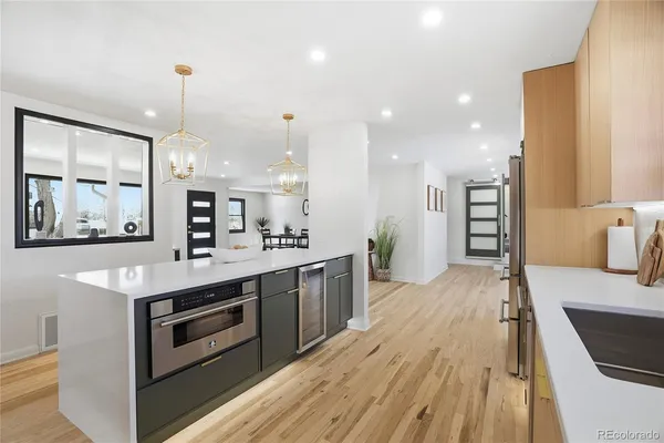 a kitchen with stainless steel appliances kitchen island granite countertop a stove a sink and white cabinets with wooden floor