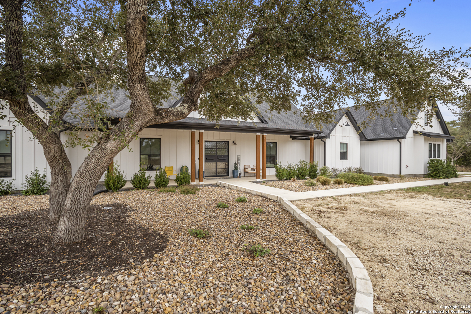 209 River Ridge Boerne, TX 78006 - Photo 4 of 60 a front view of a house with a dirt yard and a large tree