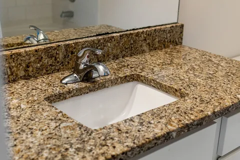 a bathroom with a granite countertop sink a toilet and a shower
