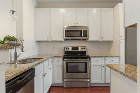 a kitchen with stainless steel appliances granite countertop grey cabinets a stove a sink and dishwasher